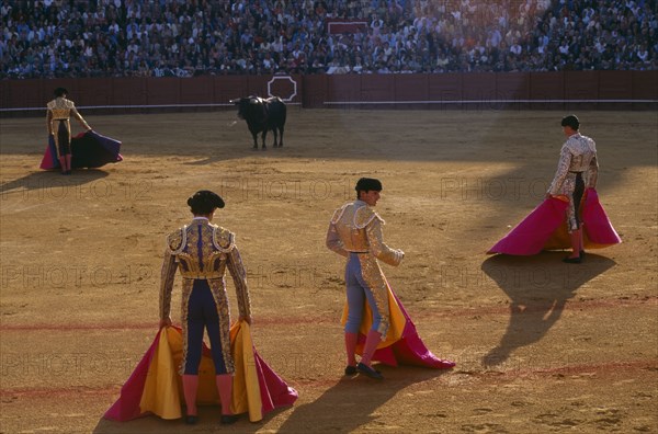 SPAIN, Andalucia, Seville, Matador in the Arenal bullring standing in front of the bull with three assistants in the foreground