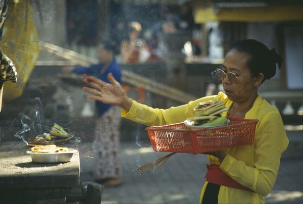 INDONESIA, Bali, Ubud, Woman worshipper at small temple  with food offerings