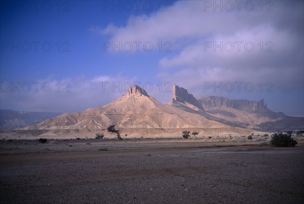 SAUDI ARABIA, Eastern Province, Howtah, Desert landscape with triangular rock formation and pinnacles in sunlight