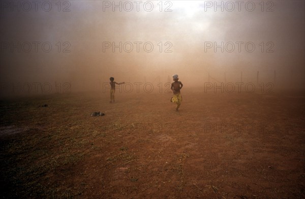 CAMBODIA, Military, Two children emerging from the dust cloud from a M: 26 Helicopter.