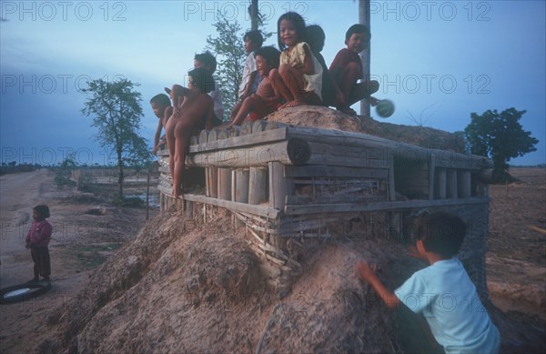 CAMBODIA, Phnom Pehn, Children playing on pillbox gun shelter made of wood and packed earth.