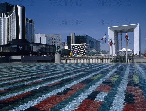 FRANCE, Il de France, Paris ,  La Defence.  La Grande Arche seen from across colourful abstract water pool