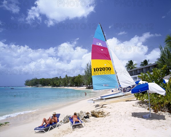 WEST INDIES,   , Barbados, Sandy beach on the West coast fringed with trees and with catamaran and sunbathers.