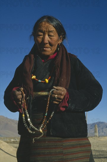 CHINA, Tibet, Shalu Monastery. Pilgrim holding prayer beads. Three-quarter portrait.