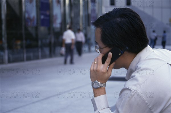 SINGAPORE, Raffles Place, Profile of city worker on mobile phone in the street in the financial centre of OUB Plaza