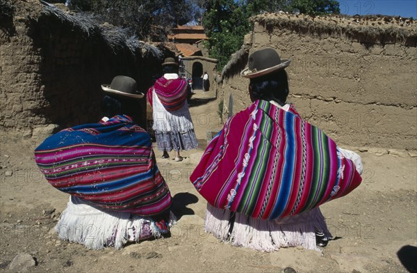 BOLIVIA, Lake Titicaca, Isla del Sol, Yumani Villagers carrying brightly coloured bundles over their shoulders. Colored