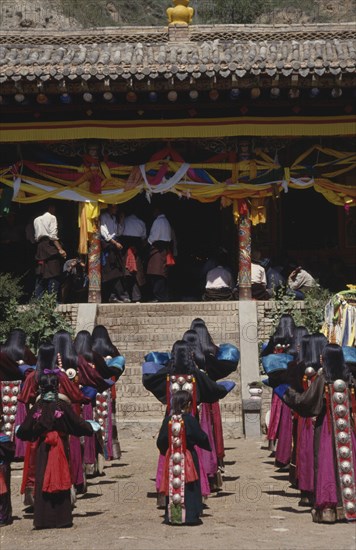 CHINA, Guizhou, Tongren, Tibetan Festival at a temple with rows of girls in traditional costume standing before steps