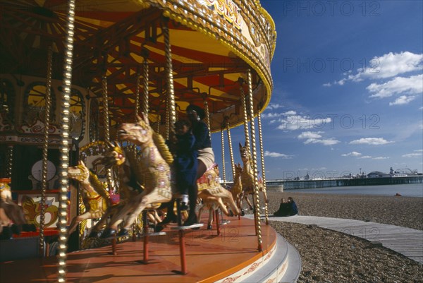 ENGLAND, East Sussex, Brighton, Child and mother sitting on a carousel on the seafront