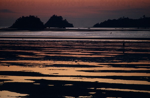 MALAYSIA, Borneo, Sabah, Kinarut Beach. Sunset reflected in the water with silhouetted islands just off shore