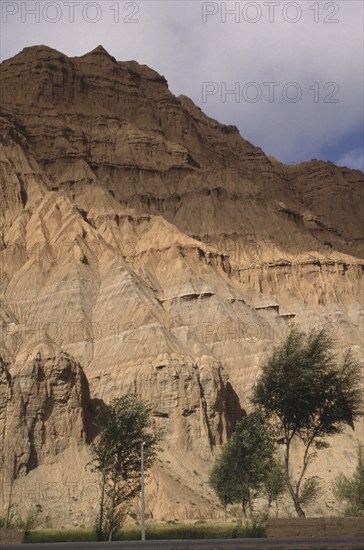 CHINA, Qinghai , Eroded rocky cliffs above wheat field in a high altitude remote valley near the Yellow River