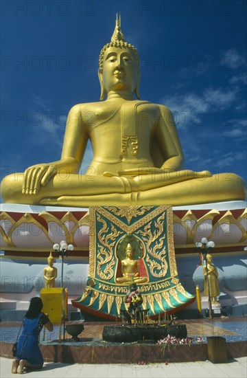THAILAND, Surat Thani, Koh Samui , Woman praying before statue of Buddha at the Big Buddha Temple on the north coast