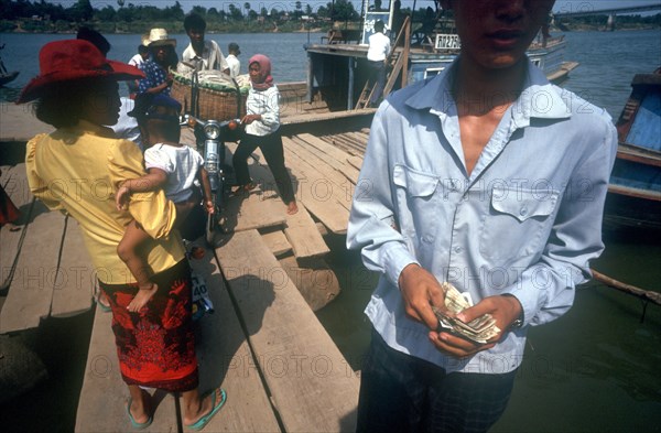 CAMBODIA, Phnom Pehn, "Tonle Sap ferry.  Man taking money in foreground, passengers boarding and disembarking."