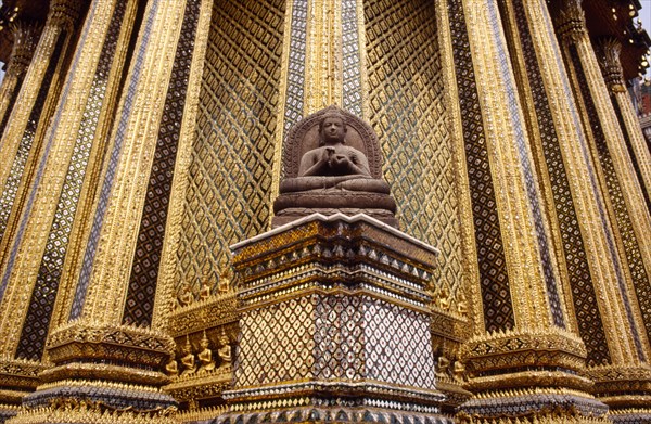 THAILAND, Bangkok, "Grand Palace, Wat Phra Kaeo. Seated Buddha statue with ornately decorated golden exterior walls of temple"