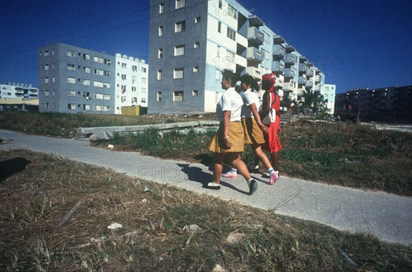 CUBA, Havana , Blocks of flats with schoolgirls walking on path in the foreground