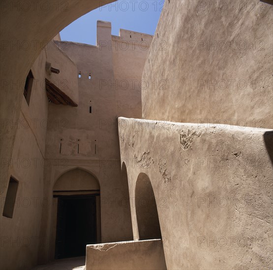 OMAN, Western Hajar, Rustaq, "Fort. Interior view of plain walls, doorway with arch and  blue sky above "