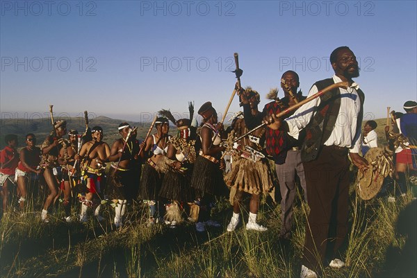 SOUTH AFRICA, KwaZulu Natal, Melmoth, Procession of bride's family at Zulu wedding in colourful dress carrying sticks and dancing