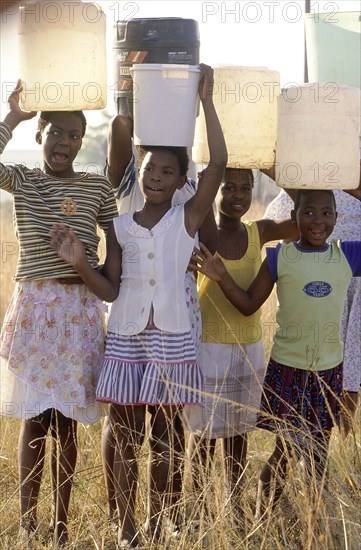 SOUTH AFRICA, KwaZulu Natal, Pietermaritzburg, "Hopewell, young girls carrying water on their heads from the Umgeni Water community water tap."