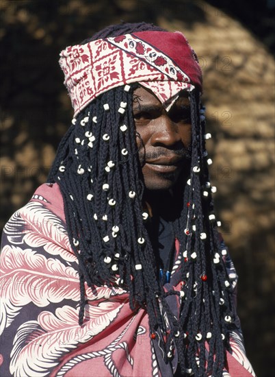 SOUTH AFRICA, Tribal People, Venda Tribesman with long plaited hair decorated with white beads and head scarf.