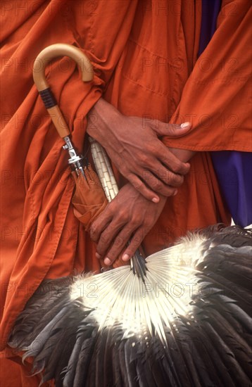 CAMBODIA, Phnom Penh, "Pochentong Airport. Buddhist monk, detail of hands, robes, umbrella and fan."