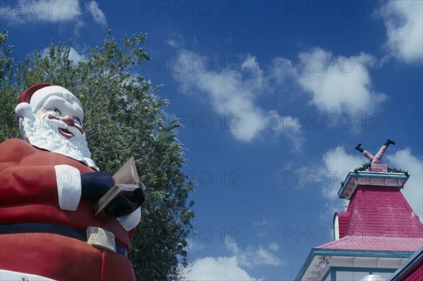 USA, Florida West , Near Fort Myers, Christmas at Shell factory. Santa statue in the foreground and chimney behind with model legs coming out of the top