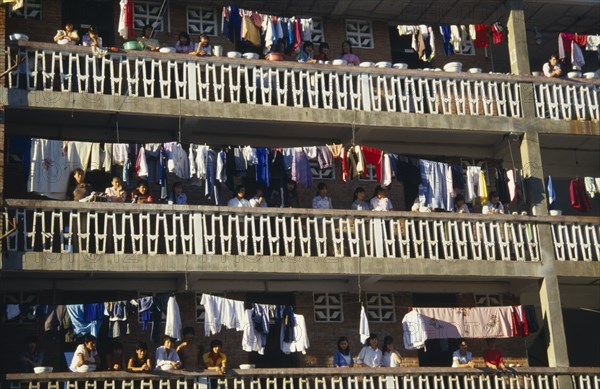 10122697 CHINA Yunan Province Jinghong Laundry hanging on apartment balconies in the Xishuangbana area with residents looking down on street.