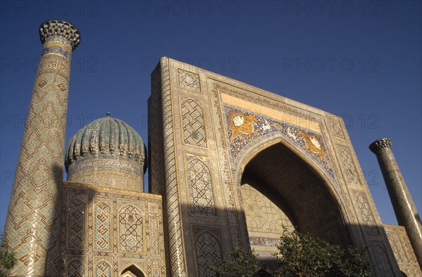 UZBEKISTAN , Samarkand, Registan , "Shir Dor Madrassah, detail of the decorated arch, dome and tower of the Muslim college partially cast in shadow"