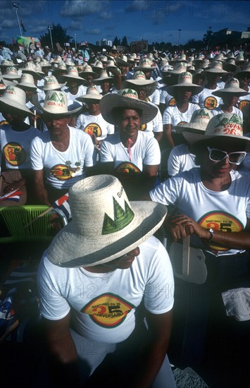 CUBA, Santiago , Crowd of seated men and women wearing matching hats and T-shirts for the July 26th celebrations