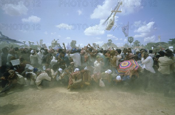 CAMBODIA, General, UN helicopter carrying Prince Ranaridth Sihanouk during the 1993 elections takes off above a crowd of his supporters leaving them in a dust storm