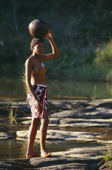 SOUTH AFRICA, KwaZulu-Natal, Near Melmoth, Zulu girl carrying pot of water on her head.