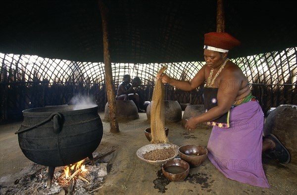 SOUTH AFRICA, Kwa Zulu Natal , Eshowe, Shakaland  Zulu woman making beer shaking sorgum from a sieve.