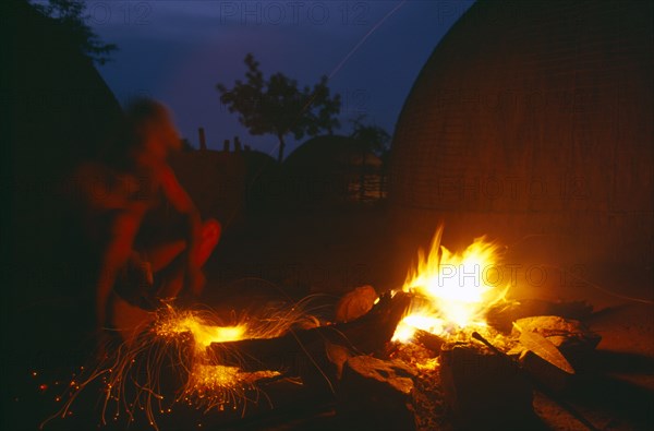 SOUTH AFRICA, Kwa Zulu Natal , Eshowe, Zulu man forging blade over a fire to make a spear.  Night shot.