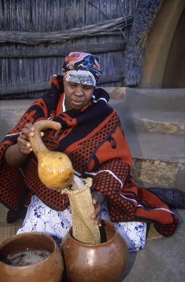 SOUTH AFRICA, Qwa Qwa, Basotho Cultural Village, Basotho woman pouring beer into a strainer from a gourd