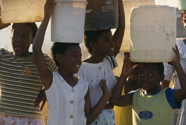SOUTH AFRICA, KwaZulu Natal, Pietermaritzburg, "Young girls carrying water on their heads drawn from the Umgeni Water community water tap, Hopewell. "