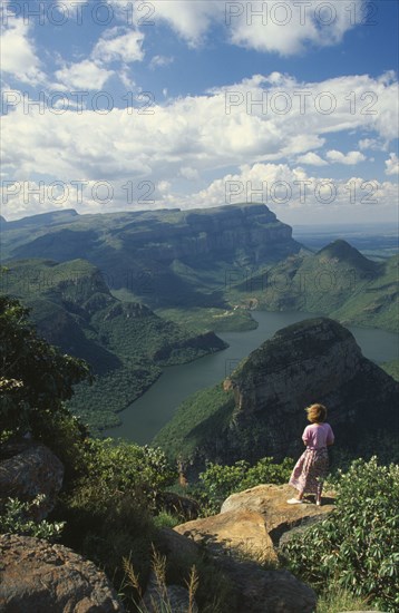 SOUTH AFRICA, Mpumalanga  , Blyde River Canyon, View from 3 Rondavels Point with a woman standing on a flat otcrop of rock looking out at view.