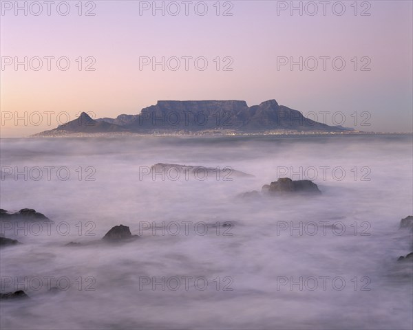 SOUTH AFRICA, Cape Province, Cape Town, View of Table Mountain at dawn taken from Bloubergstrand shore line with heavy mist.