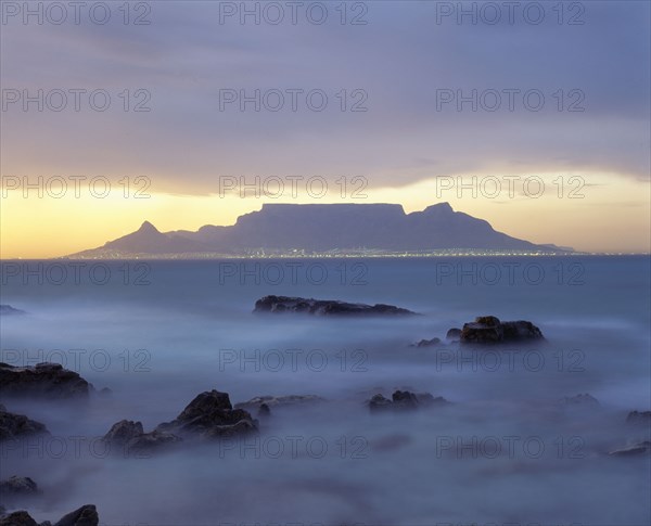 SOUTH AFRICA, Cape Province, Cape Town, View of Table Mountain at dawn taken from Bloubergstrand shore line with heavy mist.