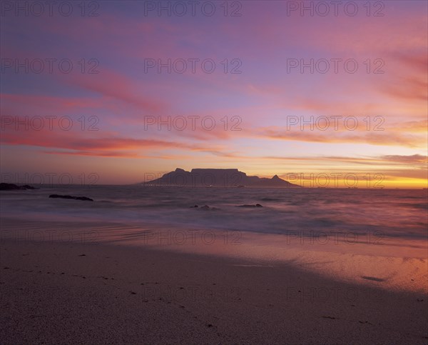 SOUTH AFRICA, Cape Province, Cape Town, View of Table Mountain at dusk taken from Bloubergstrand shore line dramatic sky.