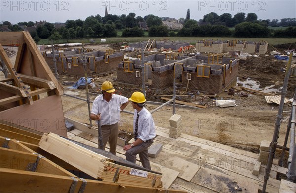 CONSTRUCTION,  , Surveyors, Surveyor wearing safety helmet talking to foreman on building construction site.