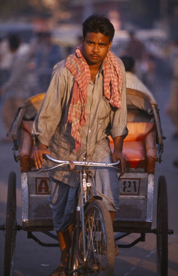 INDIA, Uttar Pradesh, Delhi, Rickshaw driver cycling on the road in the early morning