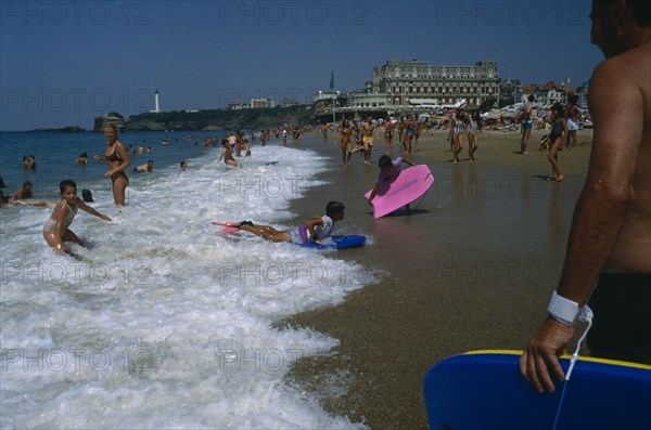 FRANCE, Aquitaine, Pyrenees Atlantiques, Biarritz.  Busy beach scene with children playing in the surf.