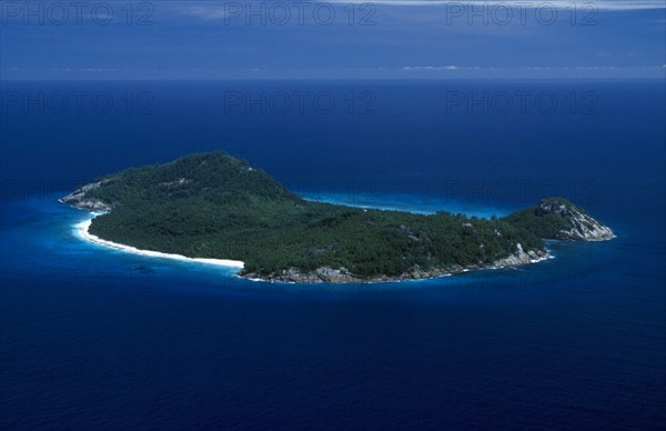 SEYCHELLES, North Island, Aerial, View over whole Island with white sand beach and interior covered by dense vegetation. Deep blue sea.