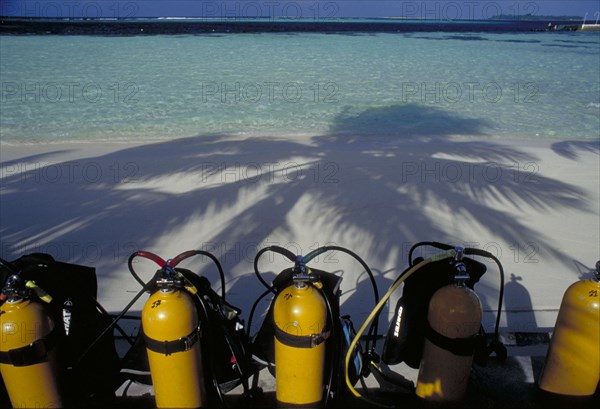 MALDIVES, Nika Island, Looking out to sea with scuba diving tanks on the beach in the shadow of coconut palm trees