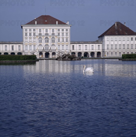 GERMANY, Bavaria,  Munich, Schloss Nymphenburg. Viewed across canal with reflection and swan on water