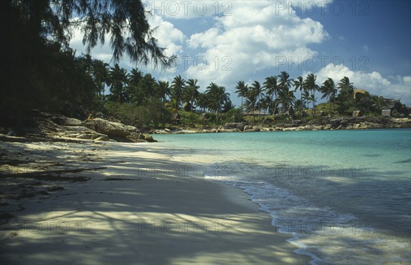 THAILAND, Koh Pha-Ngan Island, Coral Bay.  View along sandy beach toward bay with surrounding rocks lined with palms