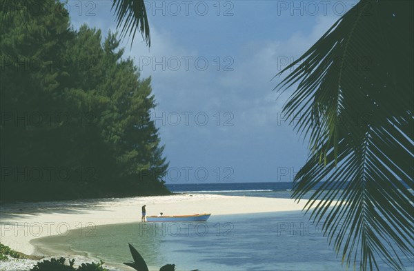 SEYCHELLES, La Digue, Beach with man and small boat at shoreline