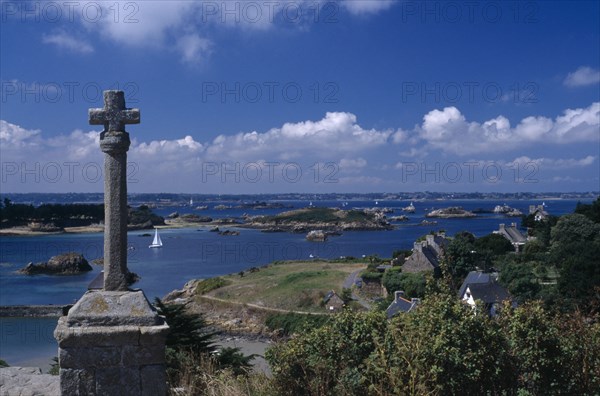 FRANCE, Brittany, Ile De Brehat, Coastal view from the Churchyard with stone cross in the foreground
