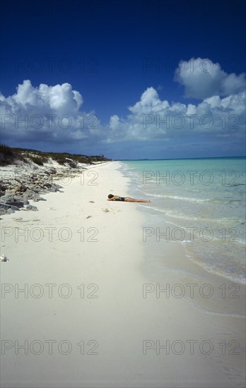 WEST INDIES, Turks And Caicos, Provo, Quiet beach with sunbather lying on the sand by the waters edge