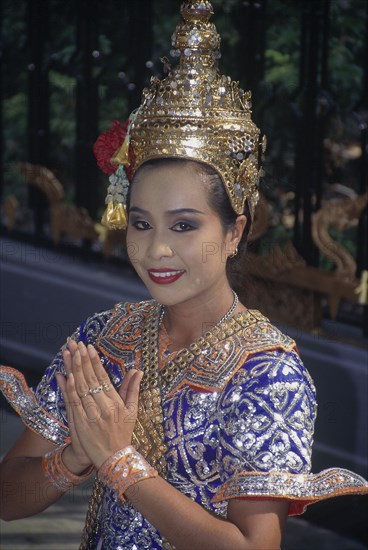 THAILAND, Bangkok, Female Temple dancer in traditional dress outside Grand Hyatt Erawan Hotel giving the traditional Thai Wai greeting