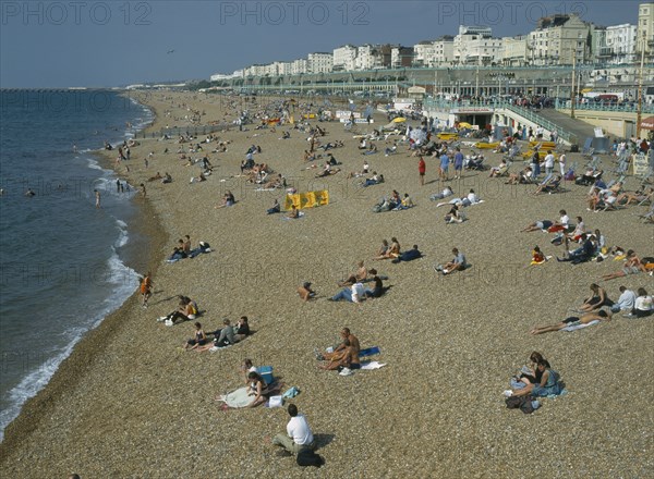 ENGLAND, East Sussex, Brighton, People sitting on the beach in summertime