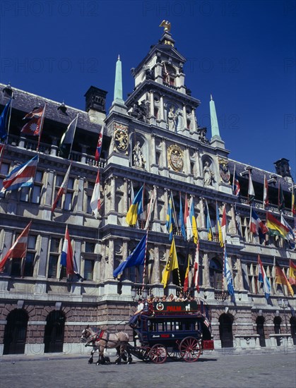 BELGIUM, Flemish Region, Antwerp, A horse drawn tourist coach in front of the Town Hall which is covered in flags.